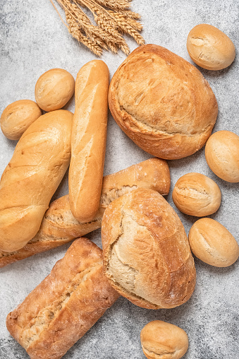 Fresh ciabatta, buns and loaf. Gray rustic background. Top view, flat lay, vertical. Selective focus.
