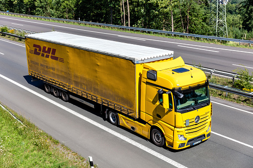Wiehl, Germany - June 26, 2020: Mercedes-Benz Actros truck with DHL curtainside trailer on motorway