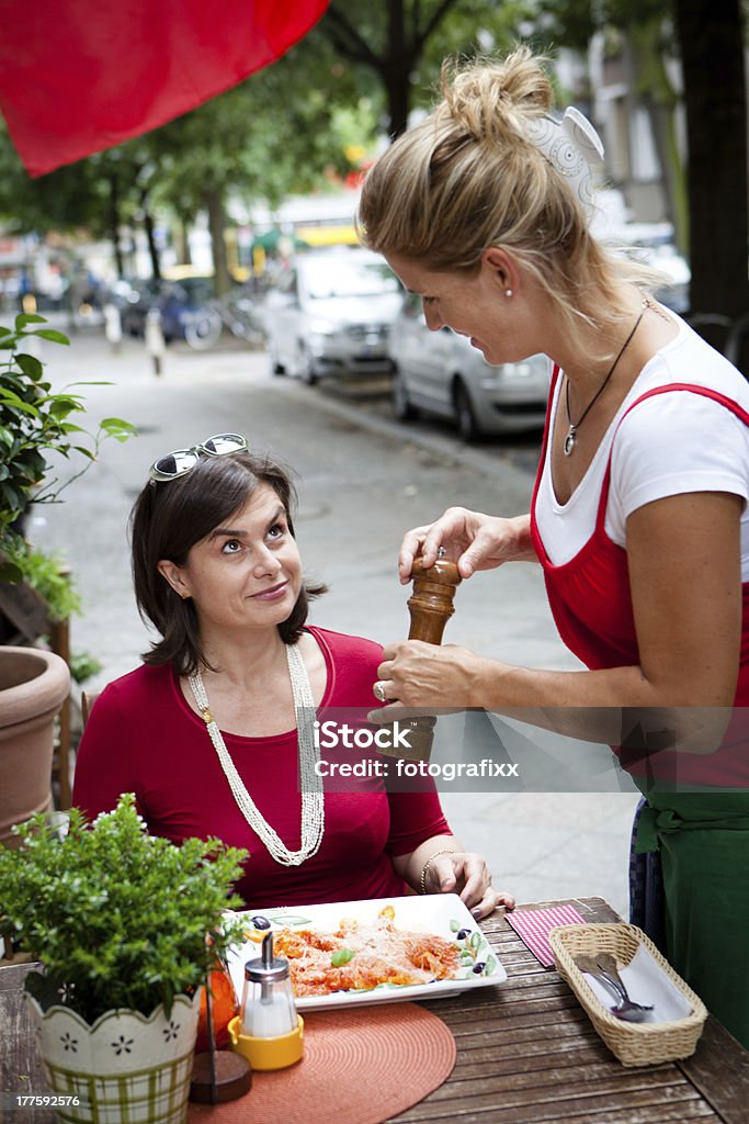 Garçonete serve o prato em um pequeno restaurante italiano - Foto de stock de Itália royalty-free