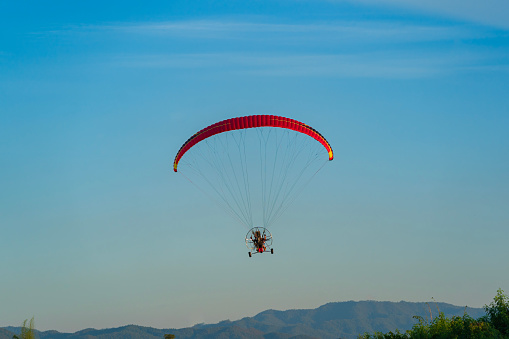 Flying with paramotor in the blue sky - Man riding paramotor in the blue sky background.