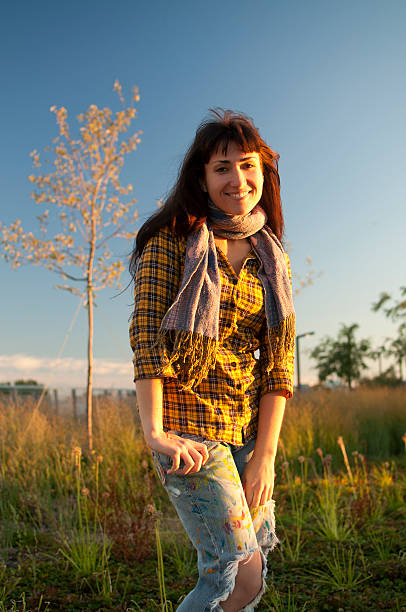 Happy student girl with yellow shirt jeans scarf in field stock photo