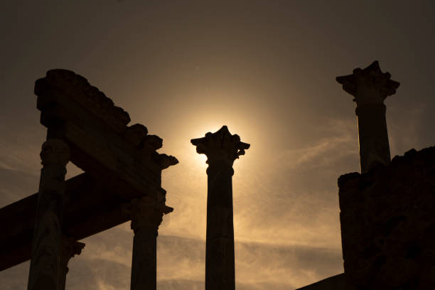 vista detallada desde abajo de los capiteles, cornisa y columnas del teatro romano de mérida, con la luz del sol a contraluz al atardecer creando un resplandor divino sobre el capitel de la columna. - badajoz fotografías e imágenes de stock
