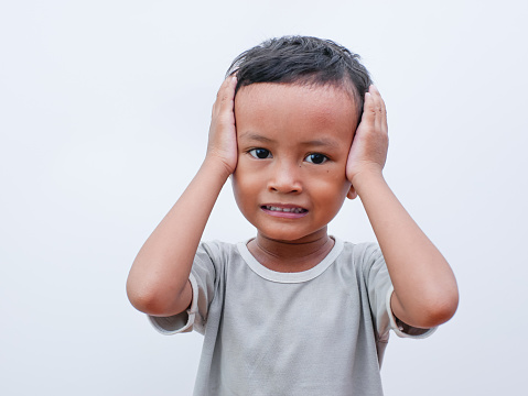 Portrait of a little asian boy holding his head with both hands. isolated on white background