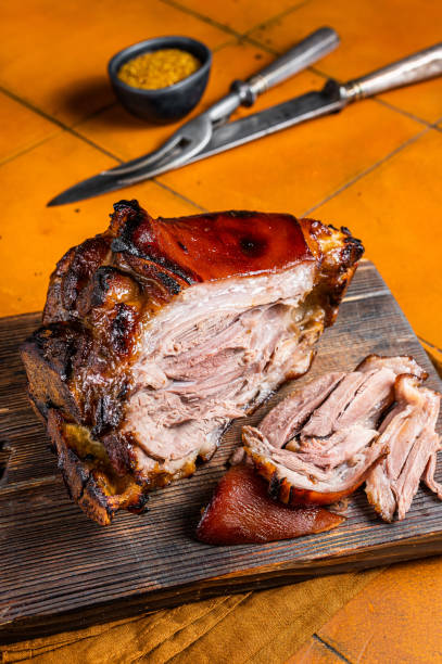 istock Roasted pork Shank, knuckle on a wooden board. Orange background. Top view 1775990823