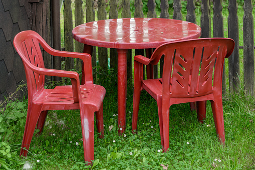 Red plastic old and abandoned garden furniture set closeup