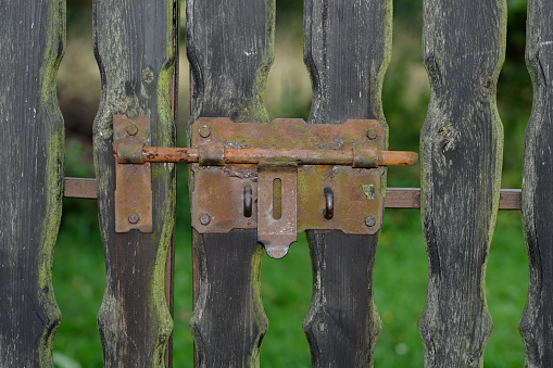 Old fence closed with a rusty bolt close up isolated