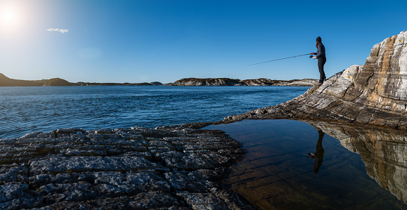 Woman spinning fishing in the sea with a rod, from the rocks