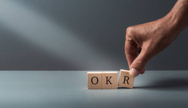 istock OKR, Objectives, Key, Results, hand putting wooden cube blocks with text OKR on a grey blue background . concept of Business target, and performance. copy space business growth by flexible management 1776012720