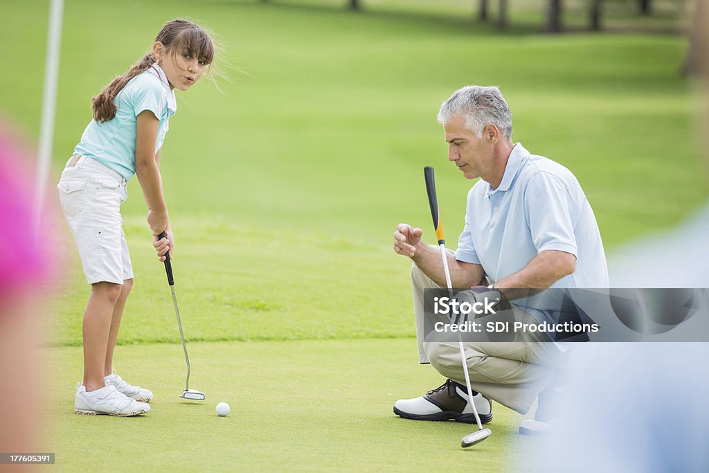 Menina aprendendo a tacada durante a aula de golfe com um profissional - Foto de stock de Golfe royalty-free