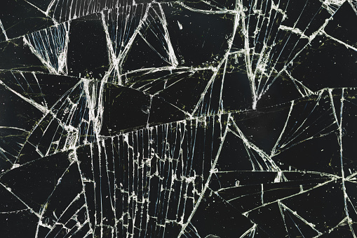 Broken, cracked glass on a black background as texture, pattern, background. Cracked smartphone screen.