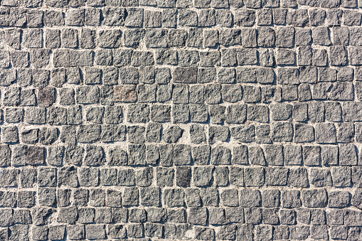 The pavement is made of gray stone in the form of squares.