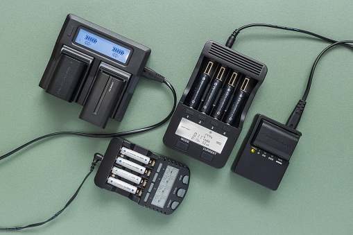 Various chargers for different types of batteries. Close-up on a light green background, top view.