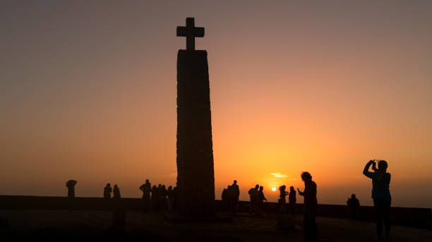 ポルトガルのカボ・ダ・ロカで日没を迎える正体不明の観光客 - sintra sunset cross outdoors ストックフォトと画像