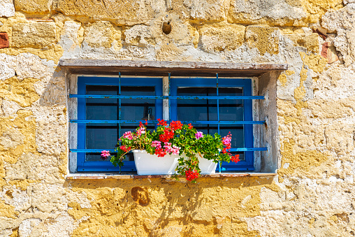 Pot with red geraniums in an old stone house in Marsala, Trapani, Sicily, Italy