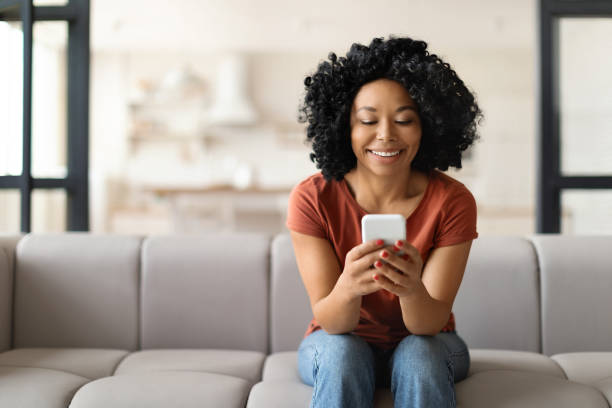 istock Young Smiling Black Woman With Smartphone Resting On Couch At Home 1776138084