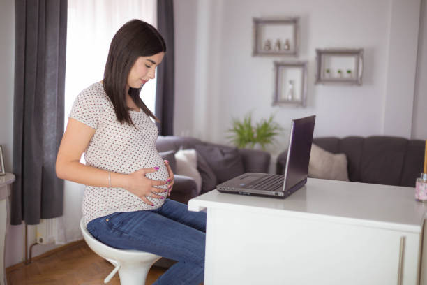 istock Pregnant woman strokes her belly while working on a laptop. 1776159399