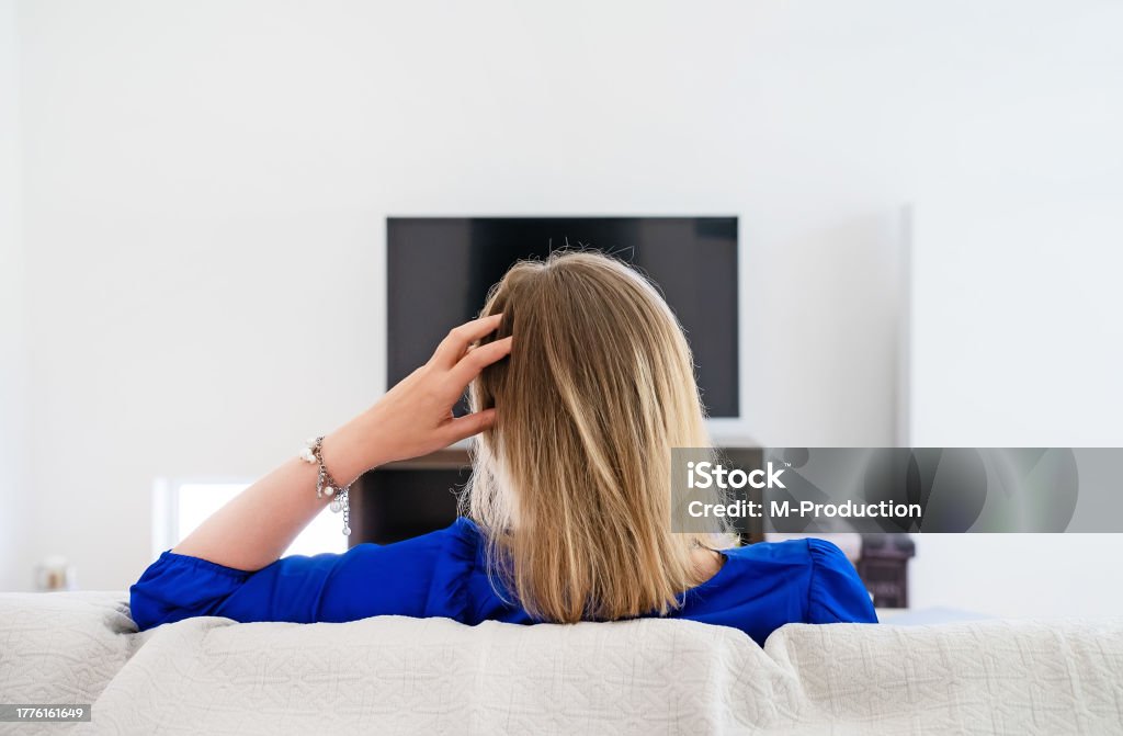 女性はテレビに映画がロードされるのを待っています。インターネット接続が遅い。 - テレビのロイヤリティフリーストックフォト 女性はテレビに映画がロードされるのを待っています。インターネット接続が遅い。 - テレビのロイヤリティフリーストックフォト