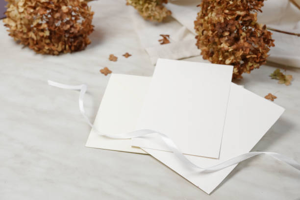 istock Wedding card mockup with dry hydrangea flowers on trendy beige marble background. Side view with copy space. 1776173105