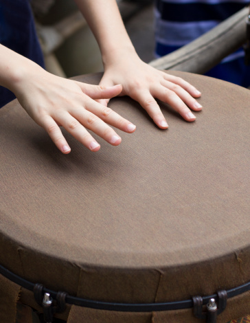 closeup of kid hands playing bongo