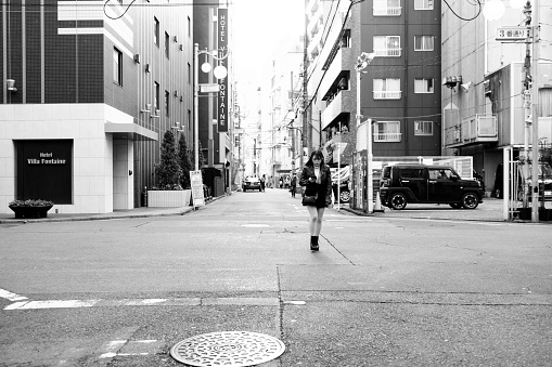 Japanese girl wearing skirt crossing a street in Shin-Okubo, a neighborhood with a South Korean vibe mixed with a little bit of Southeast Asia, also called Korea Town of Tokyo and part of Shinjuku district in Tokyo, Japan.