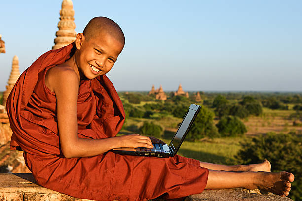 jeune moine bouddhiste à l'aide d'un ordinateur portable - hinduism monk buddhism myanmar photos et images de collection