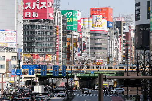 Elevated Metro train riding over Ome Kaido avenue in the busy Shinjuku district of Tokyo, Japan.