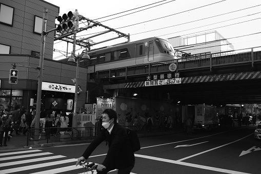 People walking and cycling on the busy Okubo Dori avenue in Shin-Okubo, a neighborhood with a South Korean vibe mixed with a little bit of Southeast Asia, also called Korea Town of Tokyo and part of Shinjuku district in Tokyo, Japan.