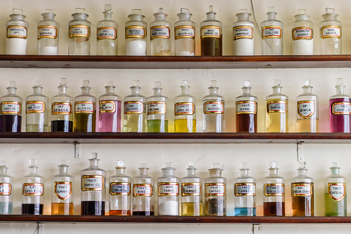 Large number of glass jars containing chemicals, herbs and tinctures within an old fashioned pharmacy chemists shop from the 19th century 1800s.