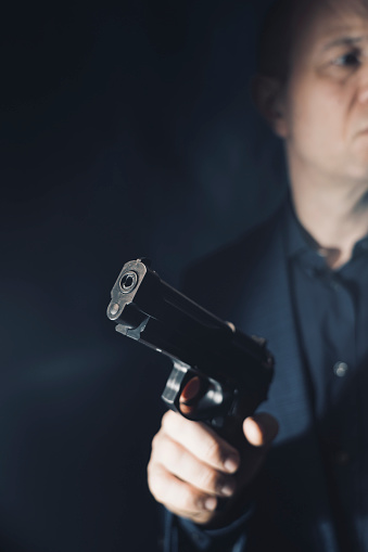 Mercenary hitman spy assasin detective with gun portrait studio shot photo.