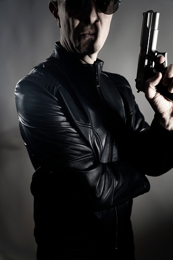 Black leather jacket hitman detective spy murderer assasin with gun portrait photo.