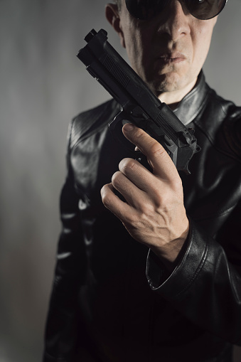 Black leather jacket hitman detective spy murderer assasin with gun portrait photo.