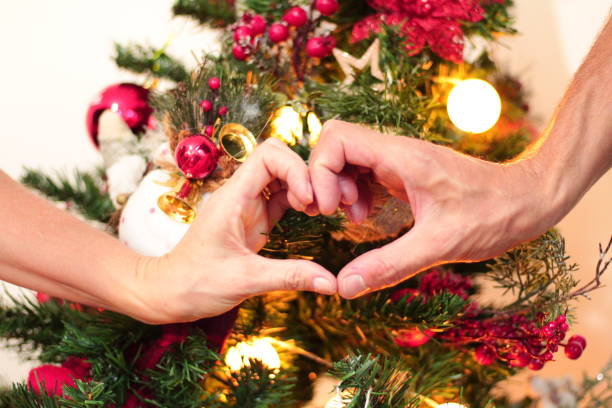 istock Couple Making Heart Symbol with their Hands in Front of a Christmas Tree 1776228012