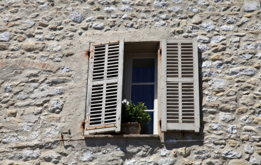 french rustic window with old wood shutters in stone rural house, Provence, France.