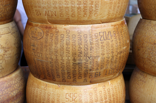 Cremona, Italy - September 7, 2022: Whole wheels of Parmigiano Reggiano cheese sold at a street stall during the farmers market in Cremona, Lombardy, Italy