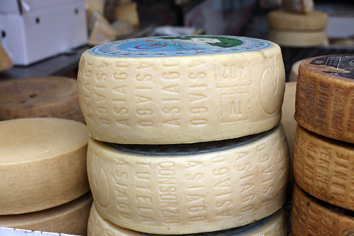 Cremona, Italy - September 7, 2022: Whole wheels of Asiago cheese sold at a street stall during the farmers market in Cremona, Lombardy, Italy