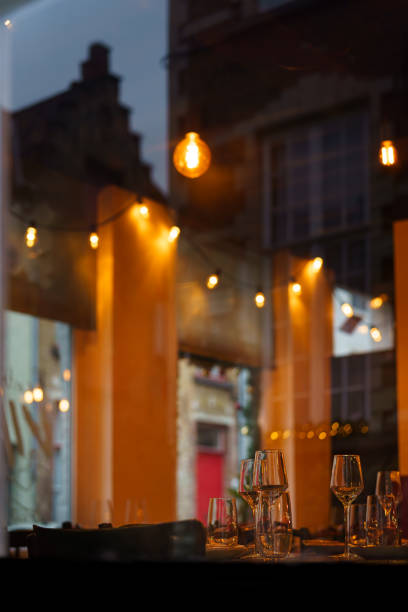 istock Looking through the window, there is a restaurant's set table adorned with Christmas decorations. The lights and the buildings on the street are reflected on the window glass. 1776247057