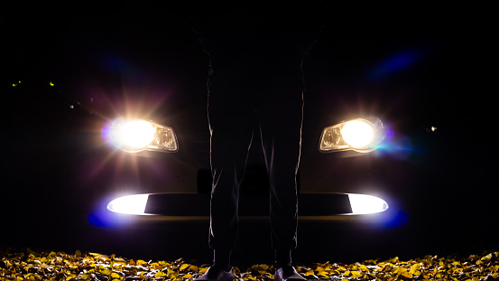 Man in the dark against the background of car headlights