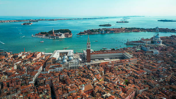 Venice (Italian: Venezia) is a city in northeastern Italy and the capital of the Veneto region. It is built on a group of 118 small islands that are separated by expanses of open water and by canals; portions of the city are linked by over 400 bridges. The islands are in the shallow Venetian Lagoon, an enclosed bay lying between the mouths of the Po and the Piave rivers (more exactly between the Brenta and the Sile).
Piazza San Marco, often known in English as St Mark's Square, is the principal public square of Venice, Italy, where it is generally known just as la Piazza ( vista aérea de venecia, italia, toma con dron de la arquitectura y el canal de venecia, vista aérea del puente de rialto, escena aérea con dron de la icónica y única plaza de san marcos o piazza san marco con el palacio ducal, la basílica y el campan