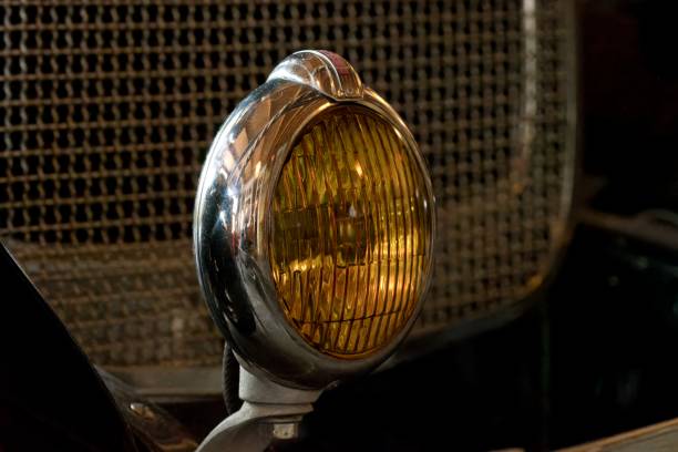 Headlamps, switched on,  and radiator grille of vintage car.