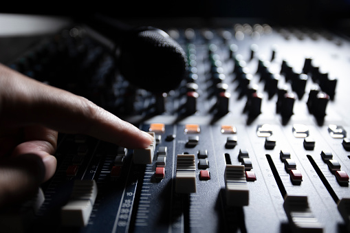 Men's hands are controlling the console of a large hi-fi system. Sound equipment. Control panel of a digital studio close-up mixer.