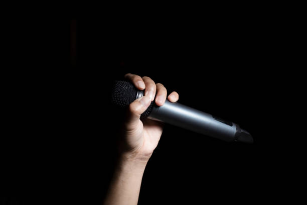istock Male hand holding microphone  isolated on black background 1776347116