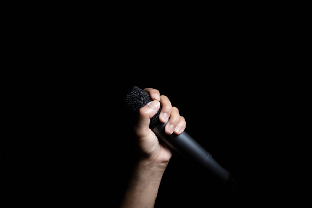 istock Male hand holding microphone  isolated on black background 1776347676