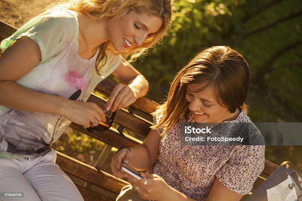 Amigos usando teléfono inteligente en el parque - Foto de stock de 20-24 años libre de derechos