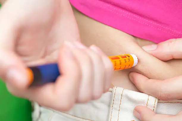 Diabetes patient make insulin injection shot by syringe in abdomen, close up