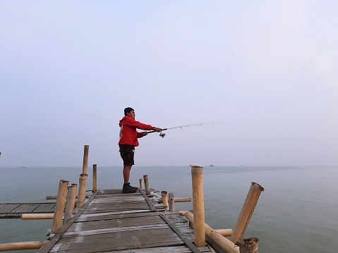 A man casting a fishing rod at sea