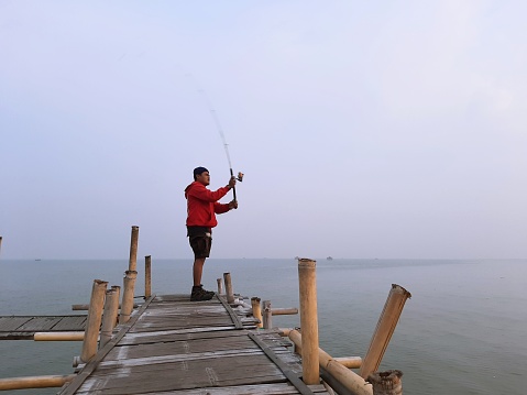 A Man casting a fishing rod at the sea