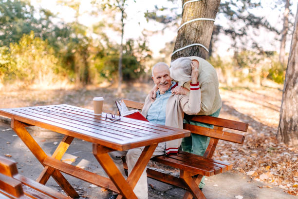 istock Old people enjoying Autumn outside in the park reading a book 1776433704