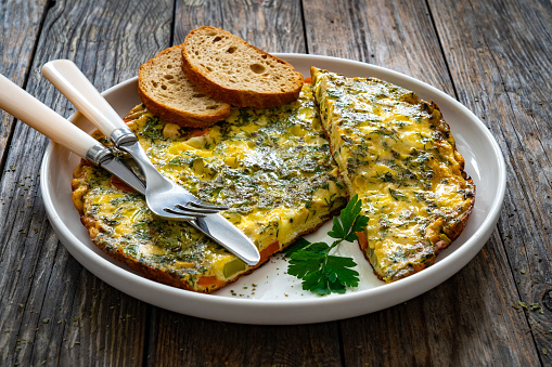 Omelette - scrambled eggs with cheese and vegetables on wooden table