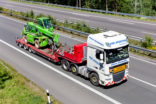 Wiehl, Germany - June 26, 2020: VHS-Spedition DAF XF flatbed truck with Merlo telescopic handler on motorway
