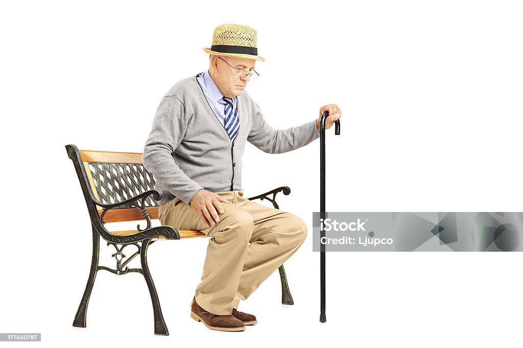 Senior man with a cane sitting on bench Senior man with a cane sitting on a bench isolated on white background Tired Stock Photo